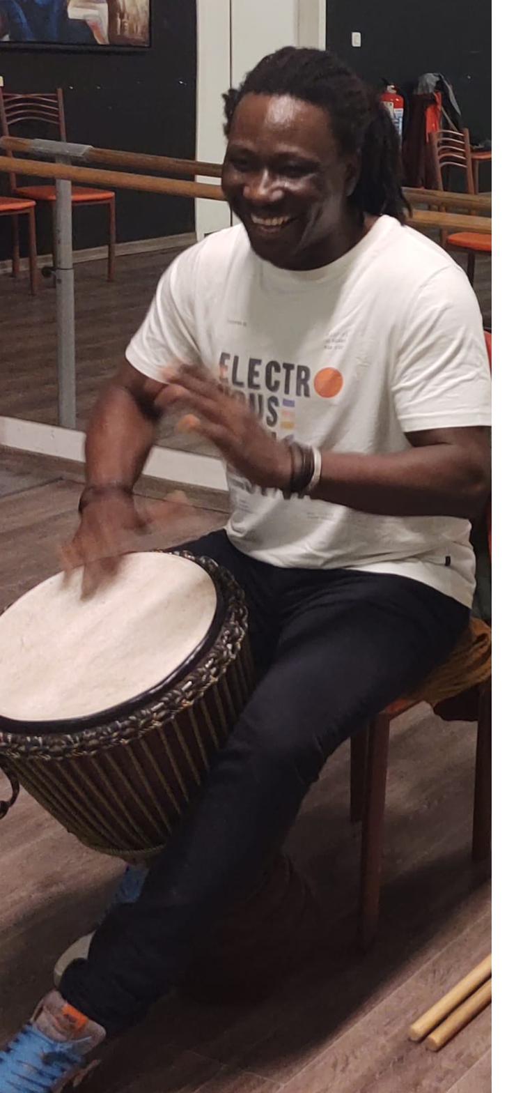 Moussa Dembélé playing djembé indoors