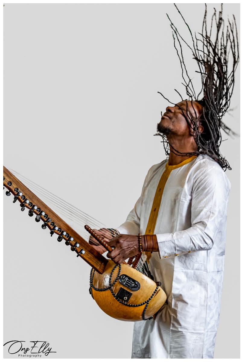 Moussa Dembélé playing the kora, dreadlocks in motion